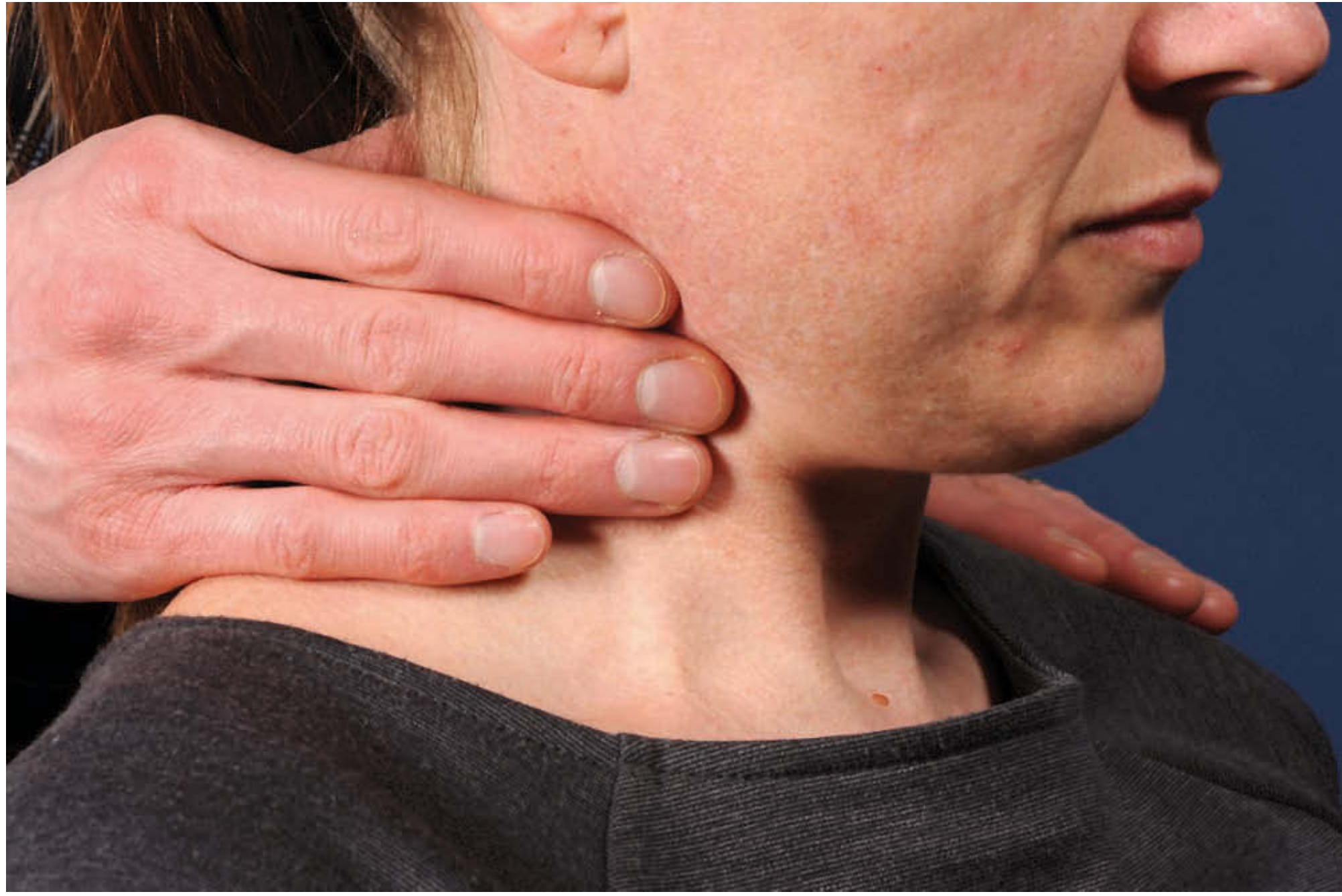 Palpation of the thyroid/neck region from behind